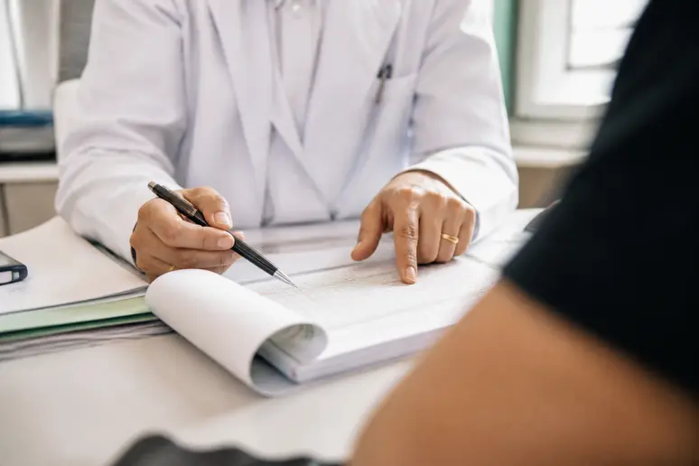 Mains d'un médecin français sur un dossier patient, illustrant l'utilisation du qSOFA.