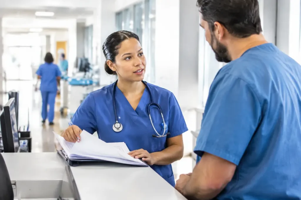 Un infirmier en pratique avancée analyse des documents médicaux au poste de soins d'un hôpital.